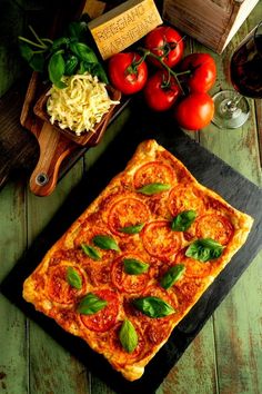 a pizza sitting on top of a wooden cutting board next to tomatoes and other vegetables