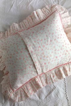 two pillows are laying on a bed with white sheets and pink floral print pillow cases