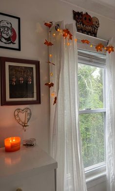 a window with white curtains and fall decorations