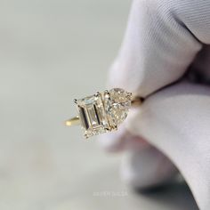 a person wearing a white glove holding an engagement ring with three stone diamonds on it