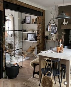 a dining room table and chairs in front of a brick wall with open glass doors