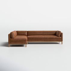 a brown leather couch sitting on top of a white floor next to a wooden frame