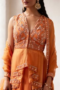 Burnt orange padded peplum tunic featuring floral hand embroidery in sequin, salli, pearl, bead work. Paired with an embroidered lehenga and an embroidered hem sheer dupatta. - Aza Fashions Sleeveless Orange Set For Festive Occasion, Orange Sleeveless Festive Set, Festive Orange Sleeveless Sets, Embroidered Peplum Dresses For Festivals, Fitted Peplum Dress With Intricate Embroidery, Orange Designer Dresses, Fitted Peplum Dress With Mirror Work, Designer Orange Dresses With Mirror Work, Designer Orange Dress With Mirror Work