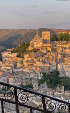 an old town is seen from the top of a hill with wrought iron railings