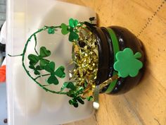 a pot filled with gold and green shamrocks on top of a wooden table next to a white container