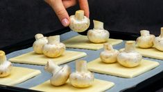 a person is placing mushrooms on top of small squares of waxed paper in front of them