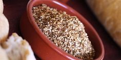 a red bowl filled with sesame seeds next to bread