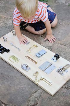 a little boy playing with some kind of board game on the ground in front of him