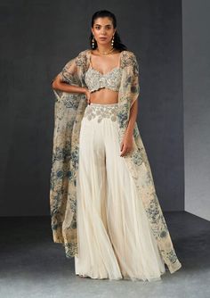 Editor's Note Presenting an exquisite ensemble: a champagne-blue cape that gracefully complements an ambi jaal embroidered bustier and an embroidered waist net sharara. This ensemble effortless... Sharara And Cape, Roce Ceremony Outfits, Embroidered Georgette Sharara With Cape Sleeves, Fitted Anarkali Set With Cape Sleeves For Reception, Bollywood Palazzo Set With Dupatta And Cape Sleeves, Eid Palazzo Set With Dupatta And Cape Sleeves, Diwali Palazzo Set With Dupatta And Cape Sleeves, Designer Cape Sleeves Sharara For Eid, Fitted Georgette Anarkali Set With Cape Sleeves