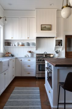 a kitchen with white cabinets and wooden counter tops, along with an area rug on the floor