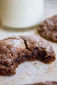 two chocolate cookies on a table next to a glass of milk