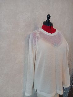 a white sweater on a mannequin with a red neckline and black top