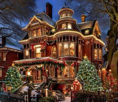 a large victorian house with christmas lights on it's windows and trees in the front yard