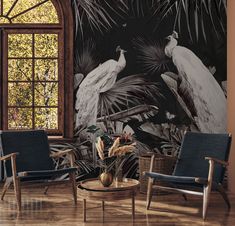 two chairs and a coffee table in front of a wall mural with birds on it