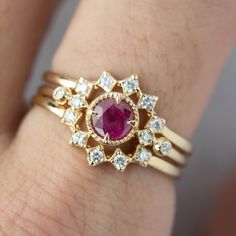 a close up of a person's hand wearing a ring with a pink stone