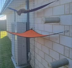 an orange hammock hanging from the side of a building next to toilet paper rolls