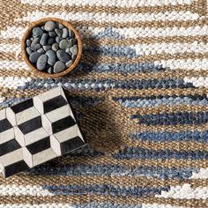 a bowl of black and white rocks sitting on top of a rug next to a checkered table cloth