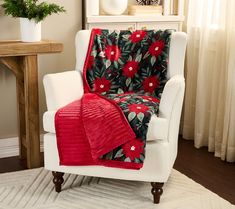 a white chair with a red blanket on top of it next to a potted plant