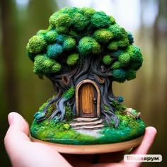 a miniature tree house made out of broccoli is shown in the palm of a person's hand