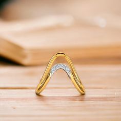 a close up of a ring on a wooden surface with a book in the background