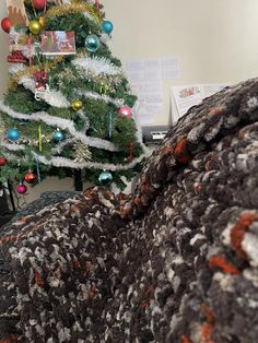 a small christmas tree in an office cubicle next to a couch and computer desk