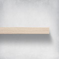 a wooden shelf sitting on top of a wall next to a white wall with no one in it