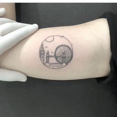 a person's arm with a tattoo on it that has a ferris wheel in the background