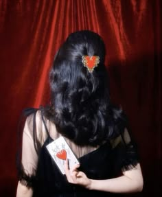 a woman with long black hair holding playing cards