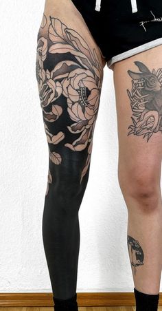 a person with tattoos on their legs and leggings, standing in front of a wall