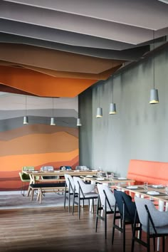 an empty restaurant with tables and chairs in front of a wall that has multicolored stripes on it