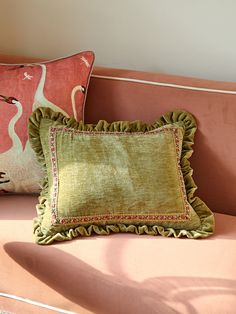 two pillows sitting on top of a pink couch next to a pillow with a flamingo design