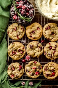 cranberry white chocolate chip cookies on a cooling rack next to a bowl of whipped cream