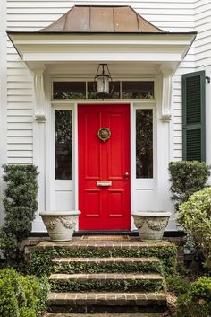 a red front door with two planters on the steps