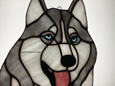 a stained glass husky dog with blue eyes and tongue hanging from a hook on a wall