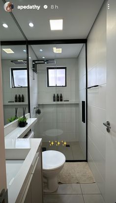 a bathroom with a toilet, sink and mirror in it's center wall is shown