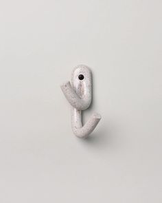 a white object that looks like the letter j is made out of clay and has an eye