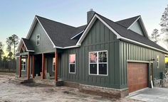 a green house with two garages in the front and one on the other side