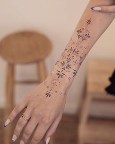 a woman's hand with a tattoo on the wrist and flower designs on it