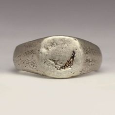 This handmade signet ring has a little 1.2mm Champagne diamond bead set for a subtle sparkle. The face is 10x10mm with a tapering shank for comfort.  Made by casting recycled sterling silver in beach sand, it has a lovely chunky feel. The sand mould creates the texture you can see on the ring. The ring pictured is a size M. Your ring will be made to order and each one comes out differently.  The rustic and irregular nature of our sandcast range comes from Justin's own technique; as the name suggests each ring is cast in beach sand. With a different mould used each time, every ring is totally unique - make it that little bit more special by sending us your own beach sand.   You can buy the mould the ring is cast in if you like. If you would like to use some of your own metal or sand please Minimalist Hand Forged Engraved Promise Ring, Minimalist Hand Forged Signet Ring For Anniversary, Minimalist Hammered Signet Ring As Gift, Minimalist Silver Hand Forged Engraved Ring, Minimalist Silver Engraved Ring Hand Forged, Minimalist Hand Forged Sterling Silver Engraved Ring, Minimalist Hand Forged Silver Engraved Ring, Minimalist Stamped Sterling Silver Signet Ring, Minimalist Stamped Signet Ring For Promise