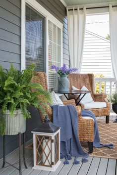 a porch with wicker chairs and plants on the front porch, along with a blue blanket