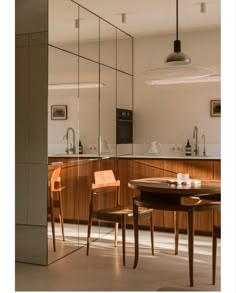 a kitchen with a table and chairs next to a mirror on the wall in front of it