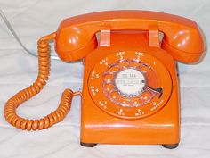 an orange telephone sitting on top of a white sheet