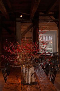 a wooden table topped with a vase filled with red flowers