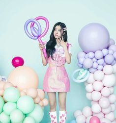 a woman in pink dress standing next to balloons