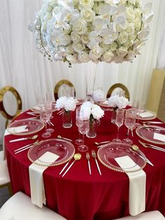 a red table with white flowers and place settings