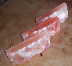 two pieces of pink soap sitting on top of a wooden table