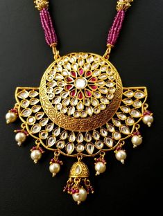 Look beautiful and feel beautiful wearing this gorgeous Indian kundan and pearl pendant necklace in chandbali design. Bright yellow gold colored crescent moon surrounds a stunning pattern of tear drop shaped kundan, which catches the light so nicely! The necklace is outstanding - lush and full multi strand necklace of sparkly faceted red crystals alternating with glowing, delicate tiny pearls. Matching jhumka earrings with pearls and red crystal accents, and clear and red stones. Effect is stunn Festive Kundan Temple Jewelry Necklace With Round Pendant, Round Kundan Necklace With Latkans For Festivals, Festive Temple Jewelry Kundan Necklace With Round Pendant, Festive Temple Style Kundan Necklace With Round Pendant, Diwali Kundan Necklace Pendant With Latkans, Festival Kundan Necklace With Latkans, Eid Round Kundan Temple Necklace, Heavy Chandbali Necklaces For Eid, Bollywood Style Kundan Necklace With Pearl Pendant For Festivals