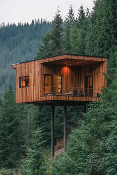 a tree house built on top of a hill surrounded by trees and mountains in the background