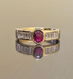 DeKara Designs Collection Metal- 18K Yellow Gold, .750. Stones- 1 Genuine Oval Ruby 0.60- 0.65 Carats. 8 Asscher Cut Diamonds F-G Color VS2 Clarity, 0.40 Carats. Size- 4-12. FREE SIZING Art Deco Inspired Oval Ruby Asscher Cut Diamond Engagement Ring Handmade in 18K Yellow Gold. The ring features an amazingly fiery oval ruby that is bezel set in the center. The sides of the ring has four amazing asscher cut diamonds that are all professionally channel set. The yellow gold is very rich and complim Yellow Gold Ruby Ring With Channel Set Diamonds, Ruby Ring With Channel Set Diamonds In Yellow Gold, Timeless Yellow Gold Ruby Ring For Wedding, Gold Ruby Wedding Ring With Center Stone, Gold Ruby Ring Channel Set For Anniversary, Gold Baguette Cut Ruby Diamond Ring, Gold Ruby Baguette Cut Diamond Ring, Heirloom Ruby Wedding Ring In Yellow Gold, Heirloom Style Yellow Gold Ruby Wedding Jewelry