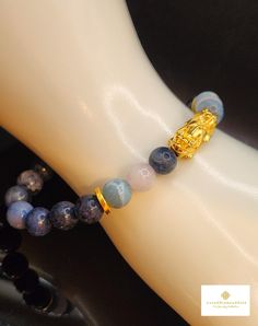 Gift yourself or your loveonce this beautiful bracelet. Crafted with 24 Karat Real Gold, Aquamarine, Larimar,  and Dumortierite. Metal: 24K Gold (Au999) Colour: Yellow Gold Gold Weight: Approximately .80g Stone Size: Approximately 8.3mm Pixiu Length: Approximately .73 Inch Metal is Made of Real 24K Gold. Never Gold Filled. Never Gold Plated. Hollow. Hallmarked. 🧧Pixiu is a powerful Feng Shui symbol of wealth. It is believed that wearing the symbol of Pixiu brings money and good fortune to its w Money Ball, Feng Shui Bracelet, Pixiu Bracelet, Feng Shui Symbols, Symbol Of Wealth, Gold Money, Protection Bracelet, Colour Yellow, Good Fortune